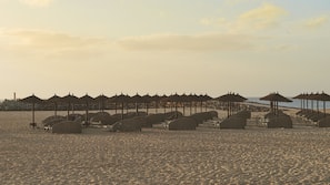 Na praia, espreguiçadeiras, guarda-sóis, toalhas de praia