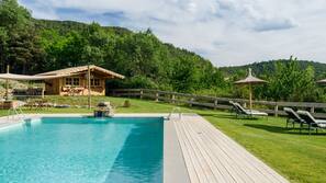 Una piscina al aire libre de temporada, sombrillas, tumbonas