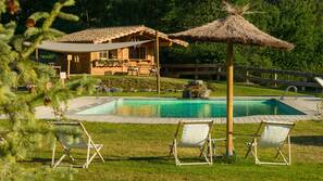 Una piscina al aire libre de temporada, sombrillas, tumbonas