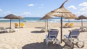 Praia particular, areia branca, espreguiçadeiras, guarda-sóis