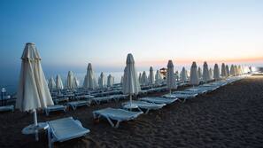 Een privéstrand, ligstoelen aan het strand, parasols, beachvolleybal