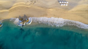 Na praia, areia branca, espreguiçadeiras, guarda-sóis