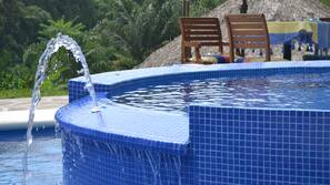 Una piscina al aire libre de temporada, sombrillas, tumbonas