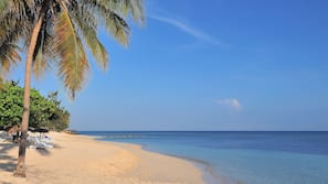 On the beach, white sand, sun-loungers, beach umbrellas