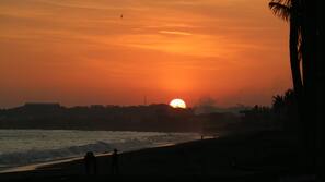 Di pantai, pasir hitam, kursi berjemur, dan payung pantai