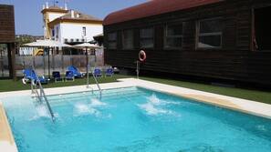 Una piscina al aire libre de temporada, sombrillas