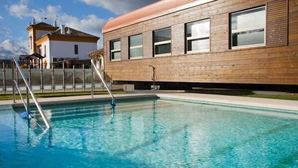 Una piscina al aire libre de temporada, sombrillas