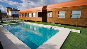 Una piscina al aire libre de temporada, sombrillas