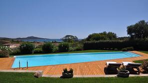 Una piscina al aire libre, sombrillas, tumbonas