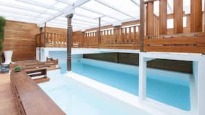 Una piscina cubierta, una piscina al aire libre, tumbonas