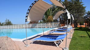 Una piscina al aire libre, sombrillas, tumbonas