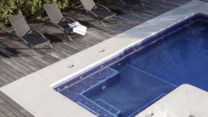 Una piscina al aire libre, sombrillas, tumbonas