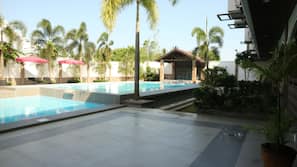 Una piscina al aire libre, sombrillas, tumbonas