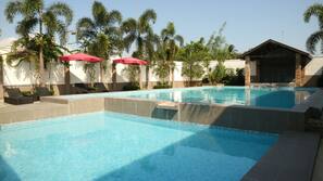 Una piscina al aire libre, sombrillas, tumbonas