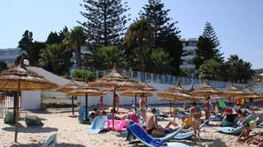 Plage, sable blanc, chaises longues, parasols