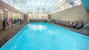 Una piscina cubierta, una piscina al aire libre, sombrillas, tumbonas