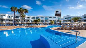 Una piscina al aire libre, sombrillas, tumbonas