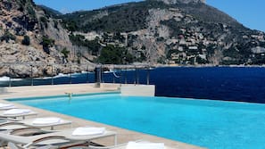 Una piscina cubierta, una piscina al aire libre, sombrillas, tumbonas
