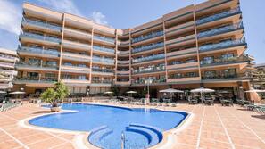Una piscina al aire libre, sombrillas, tumbonas