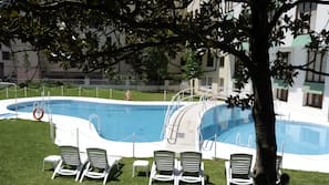 Una piscina al aire libre de temporada, tumbonas