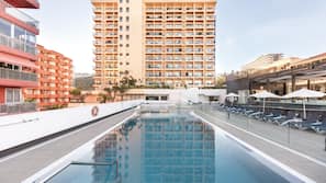 Una piscina al aire libre, tumbonas
