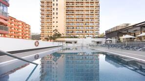 Una piscina al aire libre, tumbonas
