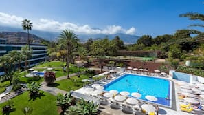 Una piscina al aire libre, sombrillas, tumbonas