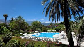 Una piscina al aire libre, sombrillas, tumbonas