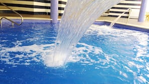 Una piscina cubierta, una piscina al aire libre, sombrillas, tumbonas