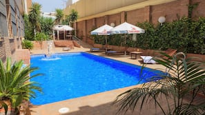 Una piscina al aire libre de temporada, sombrillas, tumbonas