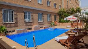 Una piscina al aire libre de temporada, sombrillas, tumbonas