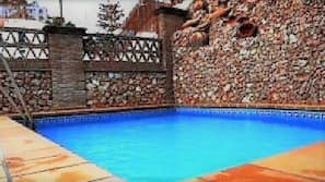 Una piscina al aire libre de temporada, sombrillas, tumbonas