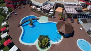 Una piscina cubierta, una piscina al aire libre, sombrillas, tumbonas