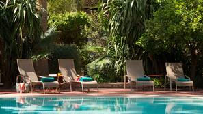 Una piscina al aire libre, sombrillas, tumbonas