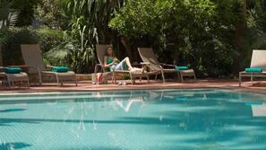 Una piscina al aire libre, sombrillas, tumbonas