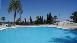 Una piscina al aire libre, sombrillas, tumbonas