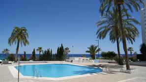 Una piscina al aire libre, sombrillas, tumbonas