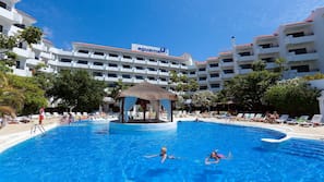 Una piscina al aire libre, sombrillas, tumbonas