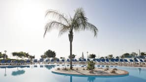 Una piscina al aire libre, sombrillas, tumbonas