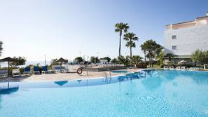 Una piscina al aire libre, sombrillas, tumbonas