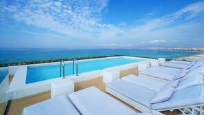 Una piscina al aire libre, sombrillas, tumbonas