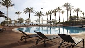Una piscina al aire libre, sombrillas, tumbonas