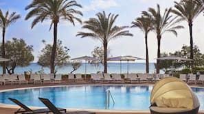 Una piscina al aire libre, sombrillas, tumbonas