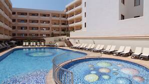 Una piscina al aire libre, sombrillas, tumbonas