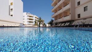 Una piscina al aire libre, sombrillas, tumbonas