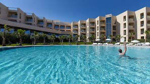Una piscina cubierta, una piscina al aire libre, sombrillas, tumbonas