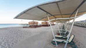 Een privéstrand, ligstoelen aan het strand, parasols, strandlakens