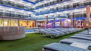 Una piscina al aire libre, sombrillas, tumbonas