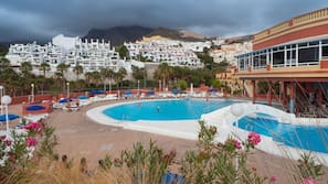 Una piscina al aire libre, sombrillas, tumbonas