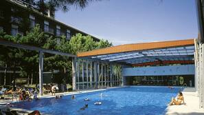 Una piscina cubierta, una piscina al aire libre, tumbonas
